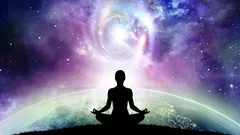 宇宙の光を背に、丘の上で瞑想する人物のシルエット